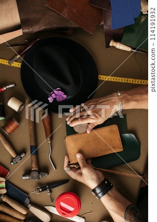 Close up of skinner craftsman working with natural leather using craft tools. 114191932