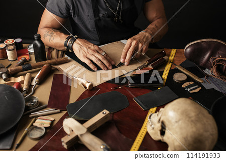 Close up of skinner craftsman working with natural leather using craft tools. 114191933