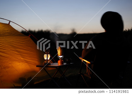 Man enjoying camping at sunset Man enjoying camping at sunset 114191981