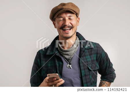 Cheerful craftsman selling online self made leather goods via smartphone. 114192421