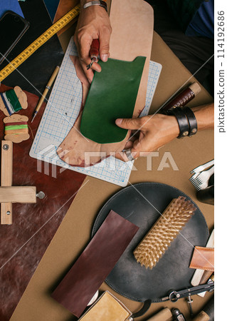 Close up of a shoemaker working with leather textile and hammer at a workshop 114192686
