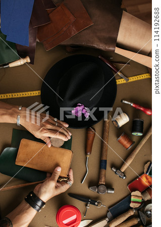 Close up of a shoemaker working with leather sample and hammer at workshop 114192688