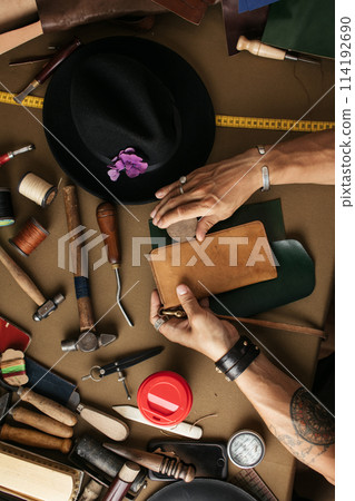 Close up of skinner craftsman working with natural leather using craft tools. 114192690