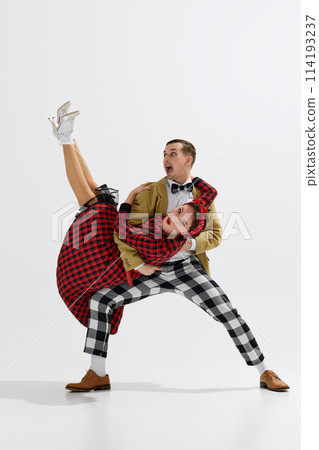 Joyous young couple in vintage attire, man and woman cheerfully dancing isolated over white studio background 114193237