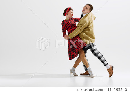 Elegant, charming young couple, man and woman in retro style clothes dancing isolated over white studio background 114193240