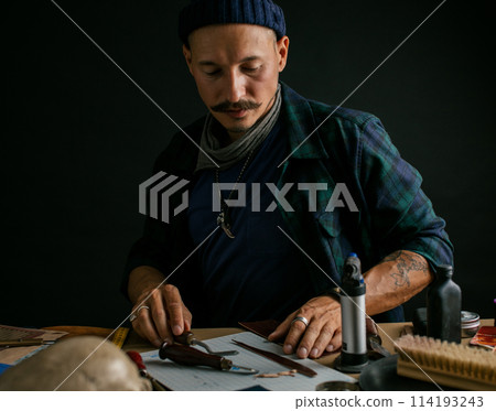 Shoemaker is repairing shoe. Shoemaker sews shoes. Cobbler workshop. 114193243