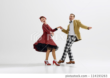 Young man and woman, couple dressed in retro-inspired outfits joyfully dancing together isolated over white studio background 114193263