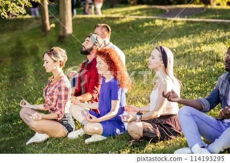 Group of adult friends meditating while practicing yoga outside in park. Group of adult friends meditating while practicing yoga outside in park. 114193295