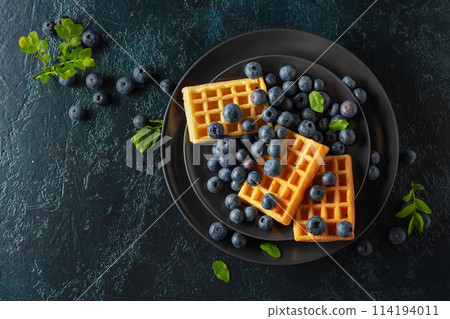 Belgian waffles with blueberries on a black plate. Belgian waffles with blueberries on a black plate. 114194011