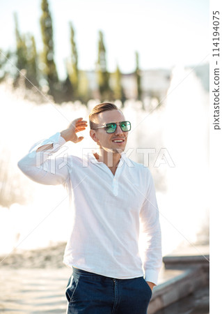 Portrait of a young confident blonde man over fountain background 114194075