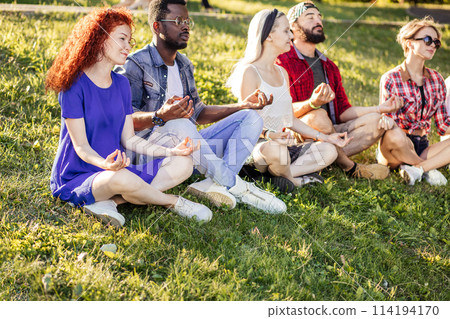 Group of adult friends meditating while practicing yoga outside in park. Group of adult friends meditating while practicing yoga outside in park. 114194170