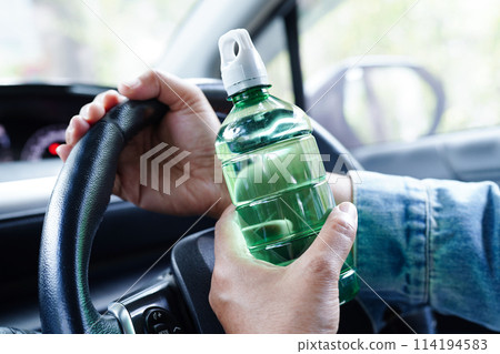 Asian woman driver hold cold water for drink in car, dangerous and risk an accident. 114194583