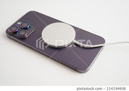 BANGKOK,THAILAND. MARCH 29 2024 MagSafe wireless magnetic charger back of iPhone 14 Pro Max, modern equipment of mobile phone. 114194606
