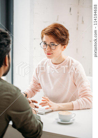 investment advisor businesswoman sitting at computer and consulting with young professional man or client investment advisor businesswoman sitting at computer and consulting with young professional man or client 114194688