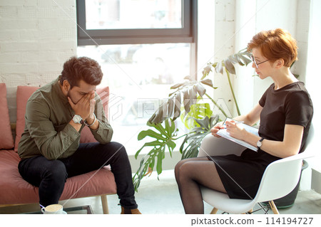 psychologist consulting indian man, writing notes during psychological therapy session psychologist consulting indian man, writing notes during psychological therapy session 114194727