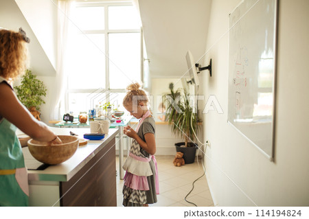 Attractive young woman and her little cute daughter are cooking at kitchen. Attractive young woman and her little cute daughter are cooking at kitchen. 114194824