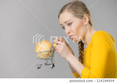Woman holding shopping cart with bread Woman holding shopping cart with bread 114194934