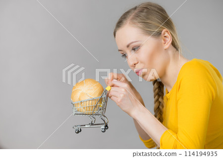 Woman holding shopping cart with bread Woman holding shopping cart with bread 114194935
