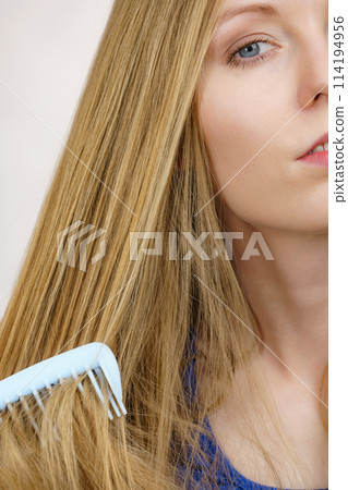 Woman combing long healthy blonde hair 114194956