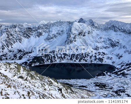 Breathtaking Aerial View Of A Snow-Covered Mountain Range Encircling A Deep, Dark Lake. The Tatry Mountains, Zakopane, Poland, 13 December 2024 Breathtaking Aerial View Of A Snow-Covered Mountain Range Encircling A Deep, Dark Lake. The Tatry Mountains, Zakopane, Poland, 13 December 2024 114195174