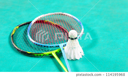White badminton shuttlecocks and badminton rackets on green floor indoor badminton court soft and selective focus on shuttlecocks and the rackets 114195968