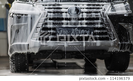 Foam drips from the bumper of a black car. Car wash. Foam drips from the bumper of a black car. Car wash. 114196379