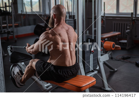 Caucasian man doing rowing exercises on a rowing machine.  114196417