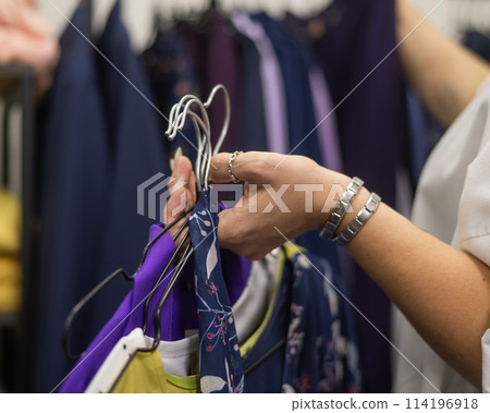 Close-up of woman's hands with hangers in a clothing store.  114196918