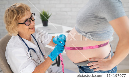 Doctor measuring the volume of a pregnant woman's abdomen using a centimeter tape.  114197077