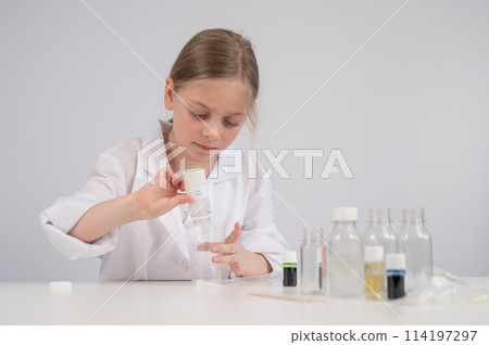 Caucasian girl doing chemical experiments on a white background. Caucasian girl doing chemical experiments on a white background. 114197297