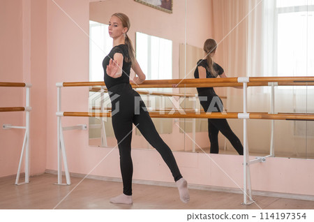 Caucasian blonde woman is practicing ballet in class. Rehearsal. Vertical photo. Caucasian blonde woman is practicing ballet in class. Rehearsal. Vertical photo. 114197354