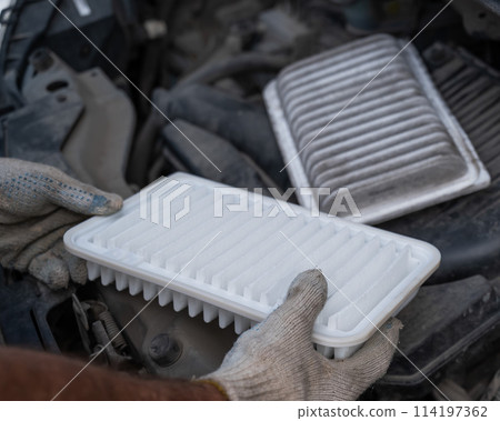 The master changes the air filter in the car engine. The master changes the air filter in the car engine. 114197362