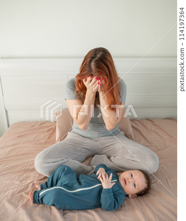 A woman sits on her child's bed and cries. Postpartum depression. Vertical photo. 114197364