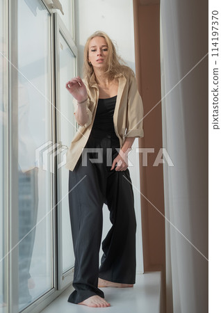Caucasian woman dancing modern dance on the windowsill. Vertical photo. Caucasian woman dancing modern dance on the windowsill. Vertical photo. 114197370