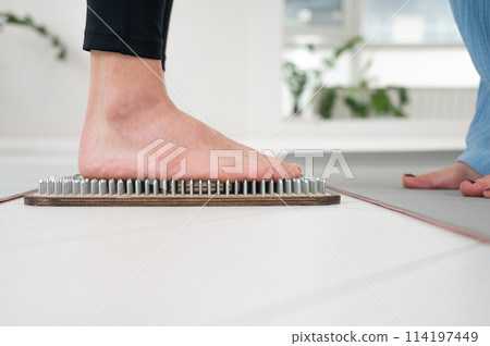 Caucasian woman stands on sadhu boards with therapist support. Caucasian woman stands on sadhu boards with therapist support. 114197449