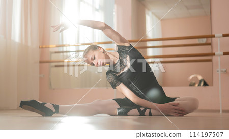 Woman in pointe shoes sits on the floor and does ballet warm-up. Woman in pointe shoes sits on the floor and does ballet warm-up. 114197507