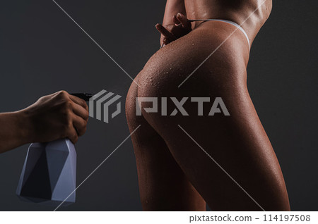 A faceless man sprays water from a polyerizer onto a woman's buttocks. A faceless man sprays water from a polyerizer onto a woman's buttocks. 114197508