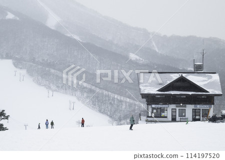 People enjoying a snowy day at a ski resort and a patrol station People enjoying a snowy day at a ski resort and a patrol station 114197520