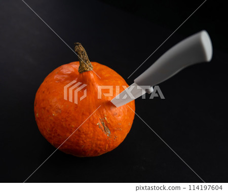 Knife in a pumpkin on a black background. Halloween symbol. Isolate. Knife in a pumpkin on a black background. Halloween symbol. Isolate. 114197604
