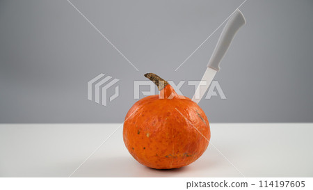 Knife in a pumpkin on a white background. Halloween symbol. Knife in a pumpkin on a white background. Halloween symbol. 114197605