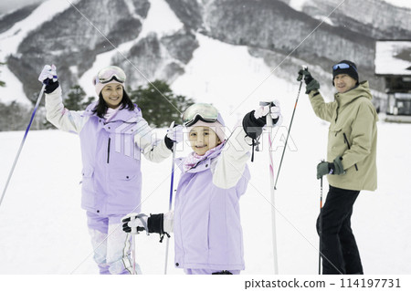 Family, parents and daughter enjoying skiing on snowy mountain 114197731