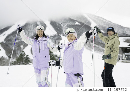 Family, parents and daughter enjoying skiing on snowy mountain 114197732