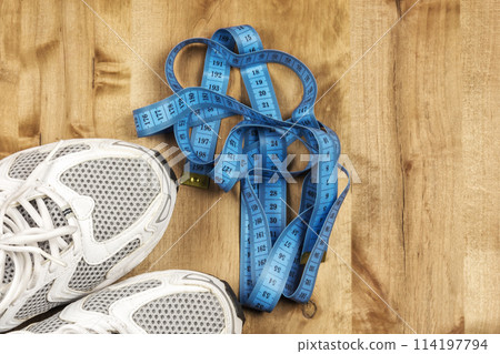 White sneakers and a centimeter on a wooden surface White sneakers and a centimeter on a wooden surface 114197794