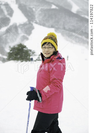 A woman in her 40s enjoying skiing on a snowy mountain 114197822
