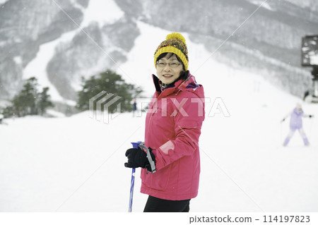 A woman in her 40s enjoying skiing on a snowy mountain 114197823