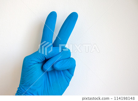 Doctor hand in sterile blue gloves. Sign victory from fingers. White background. Doctor hand in sterile blue gloves. Sign victory from fingers. White background. 114198148