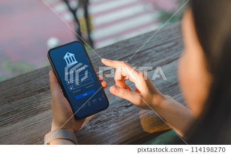Online payment concept. Over shoulder view of a woman accessing a mobile banking app on her smartphone, highlighting the ease of digital finance management. Internet bank, money transaction, fintech, Online payment concept. Over shoulder view of a woman accessing a mobile banking app on her smartphone, highlighting the ease of digital finance management. Internet bank, money transaction, fintech, 114198270