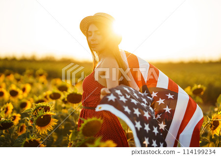 Beautiful girl in hat with the American flag in a sunflower field. 4th of July. Fourth of July. Independence Day. Beautiful girl in hat with the American flag in a sunflower field. 4th of July. Fourth of July. Independence Day. 114199234