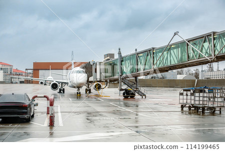 Commercial airplane docked at the gate on rainy day with boarding bridges attached Commercial airplane docked at the gate on rainy day with boarding bridges attached 114199465