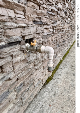 Outdoor faucet water tap with white PVC pipe and reed valve on light brick wall background texture. Copy space, water saving concept 114199780